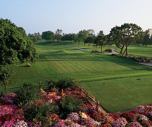 Tree-lined fairway framed by beds of blooming flowers at Los Coyotes Country Club in Buena Park, California